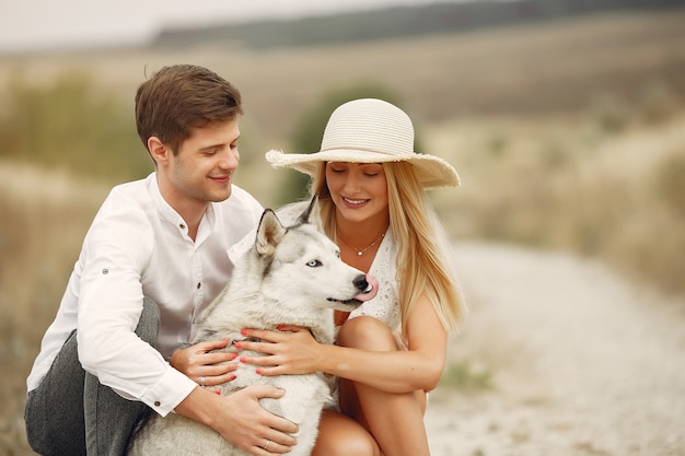 Couple in a autumn field playing with a dog