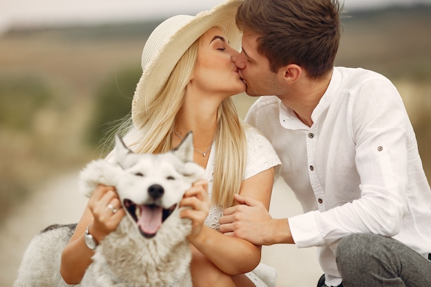 Couple in a autumn field playing with a dog