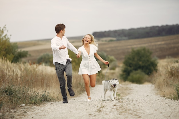 Free photo couple in a autumn field playing with a dog