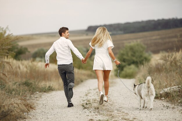 Free photo couple in a autumn field playing with a dog