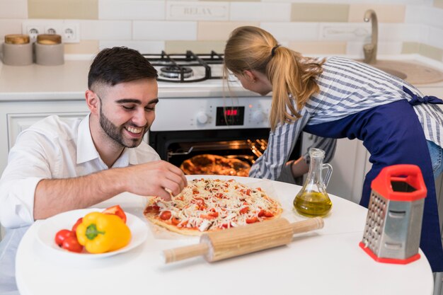 Couple baking pizza in oven 