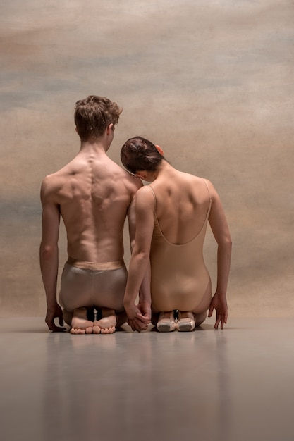 Free photo couple of ballet dancers posing over gray space