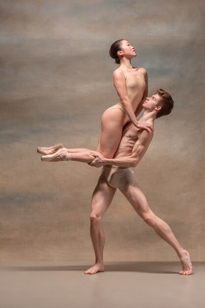 Couple of ballet dancers posing over gray space