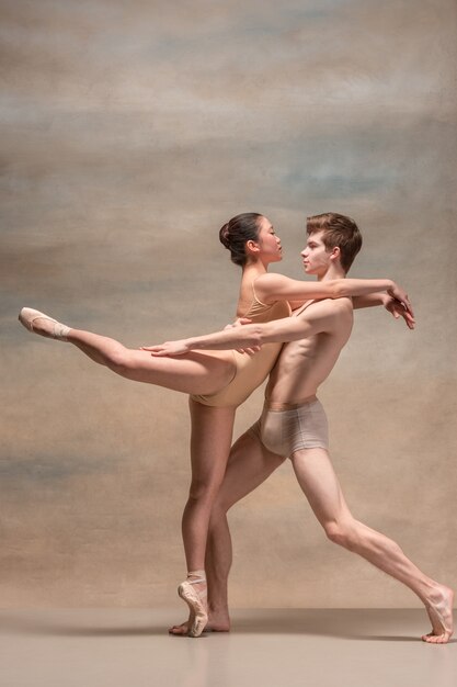 Couple of ballet dancers posing over gray.