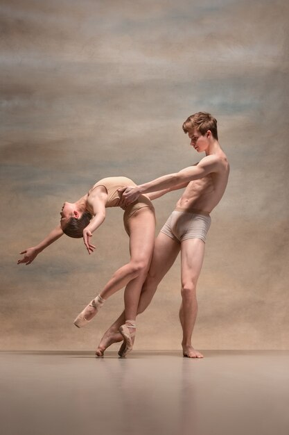 Couple of ballet dancers posing over gray.