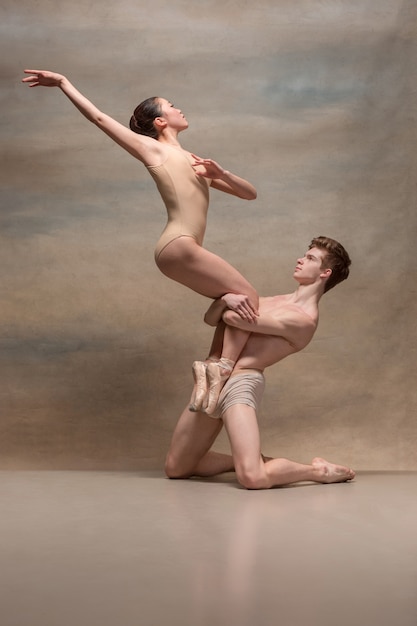 Free photo couple of ballet dancers posing over gray