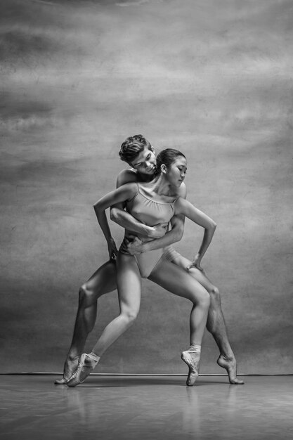 Couple of ballet dancers posing over gray