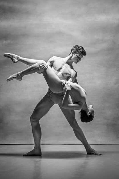 Couple of ballet dancers posing over gray