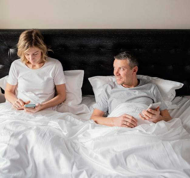 Couple in bed using mobiles