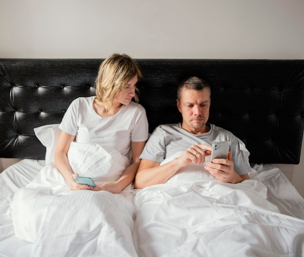 Free photo couple in bed using mobiles