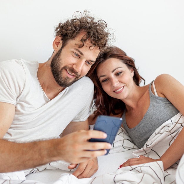 Couple in bed watching at smartphone