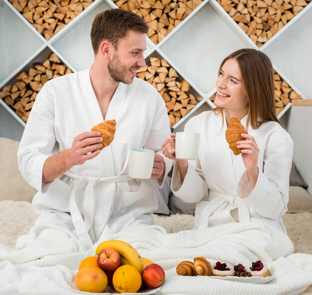 Couple in bed with bathrobes and fruits