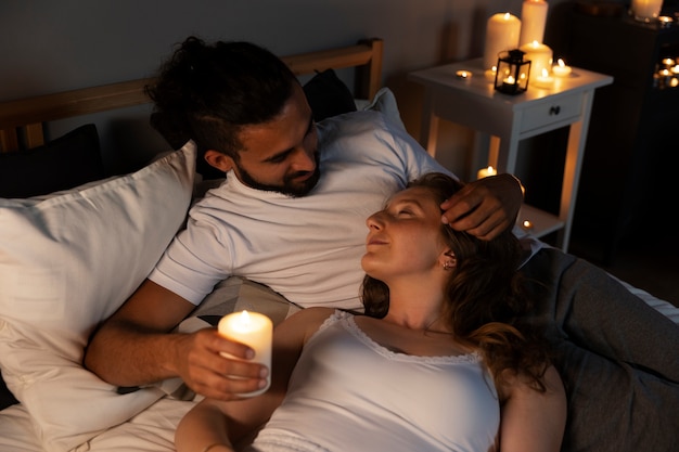 Free photo couple in bed with candle high angle