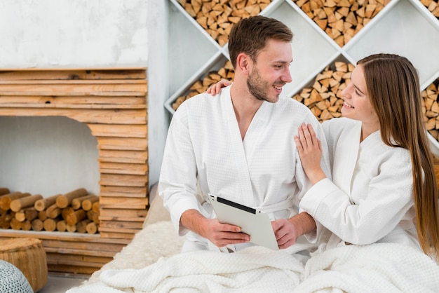 Free photo couple in bed with tablet and bathrobes