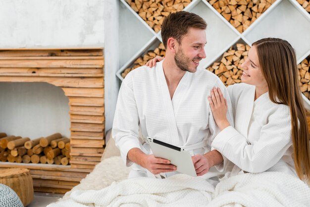 Couple in bed with tablet and bathrobes