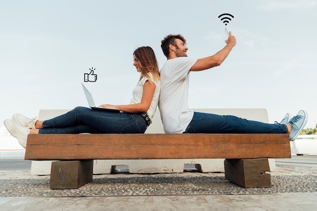 Couple on a bench using social media