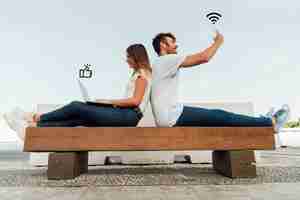 Free photo couple on a bench using social media