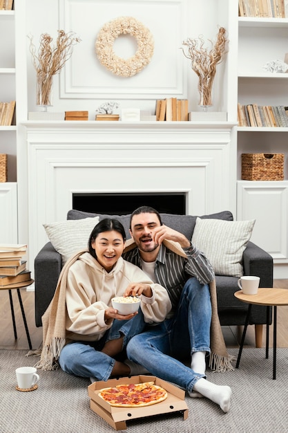 Couple in blanket eating pizza and popcorn