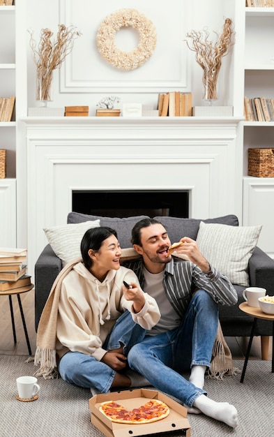 Couple in blanket eating pizza and popcorn