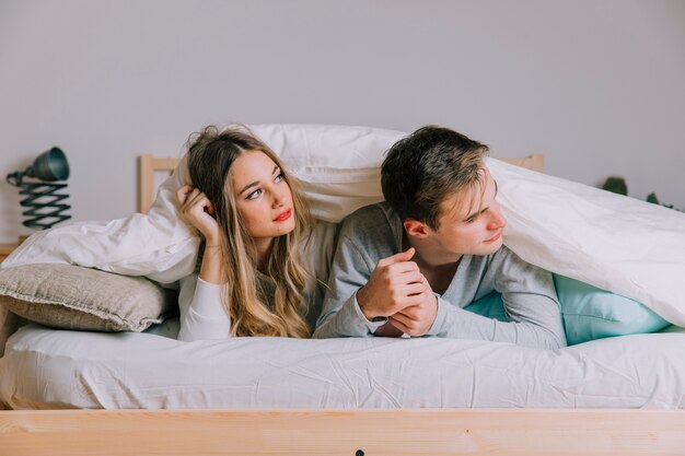 Couple under blanket looking away