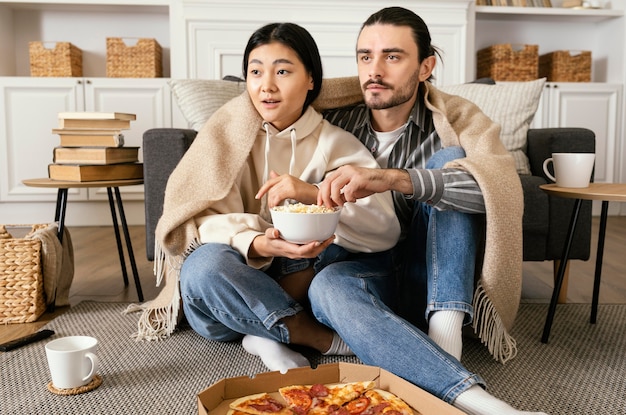 映画を見たり食べたりする毛布のカップル