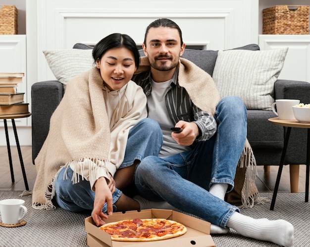 Couple in blanket watching a movie and eating