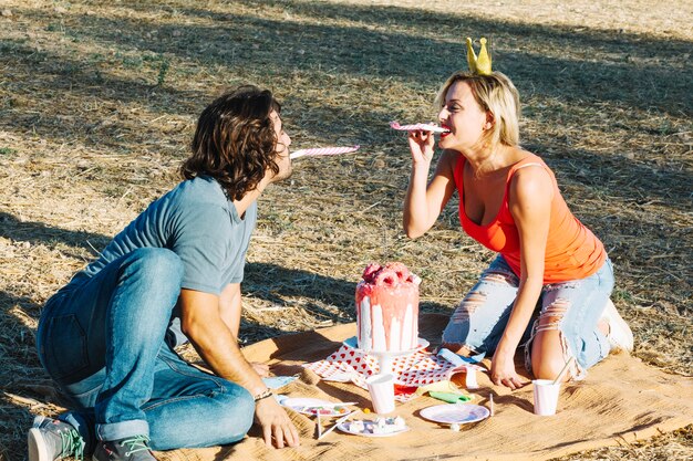 Couple blowing party horns on picnic