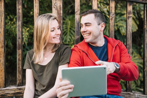 Couple browsing tablet near fence