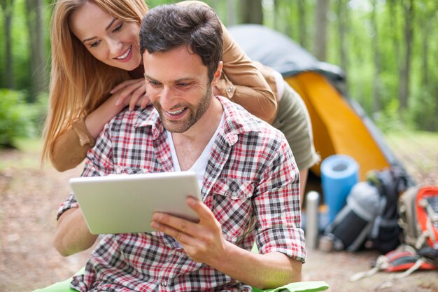 숲에서 캠핑하는 커플. 숲에서 디지털 태블릿을 사용 하여 한 쌍