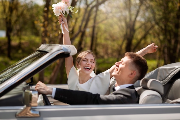 Coppia che festeggia nella loro auto appena sposata