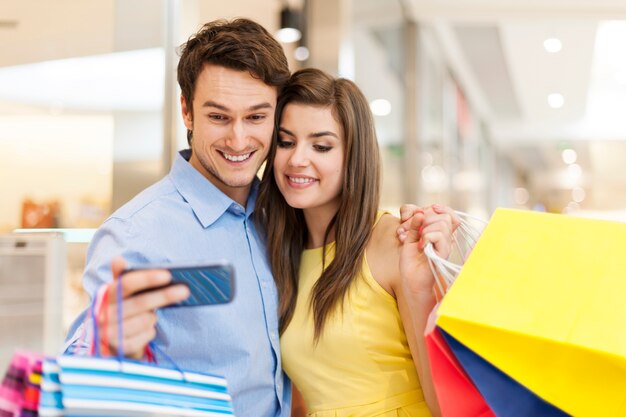 Couple checking something on the mobile phone during the shopping