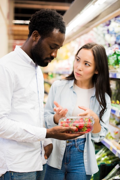 Couple choosing strawberry in grocery store