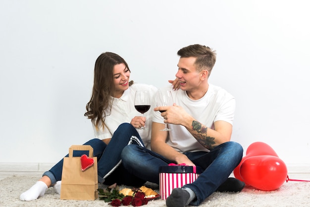 Couple clanging glasses of wine on floor 