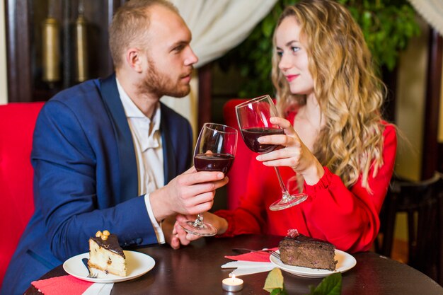 Couple clanging wine glasses at table in restaurant