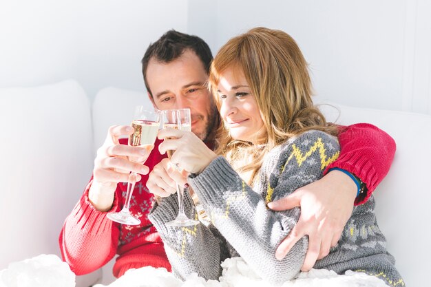 Couple clinking glasses with champagne on sofa