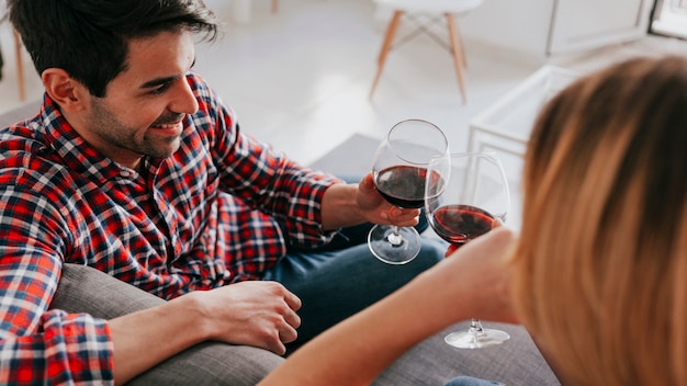 Free photo couple clinking red wine on sofa