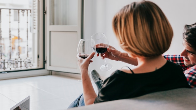 Free photo couple clinking red wine on sofa