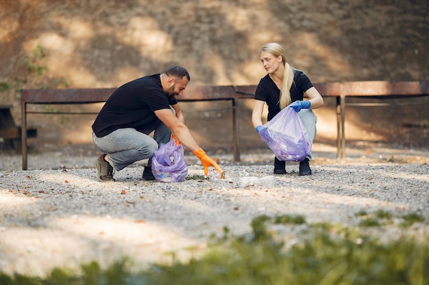 Foto gratuita la coppia raccoglie l'immondizia nei sacchetti di immondizia in parco