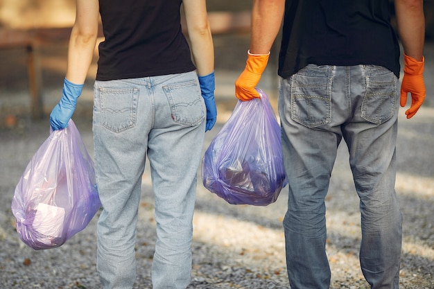 Foto gratuita la coppia raccoglie l'immondizia nei sacchetti di immondizia in parco