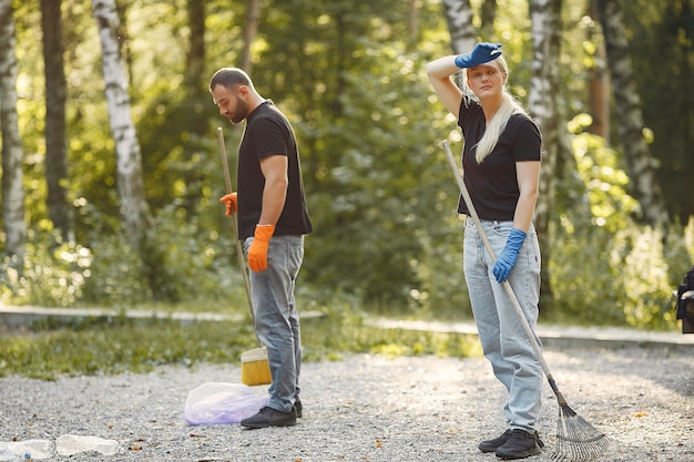 Foto gratuita la coppia raccoglie l'immondizia nei sacchetti di immondizia in parco