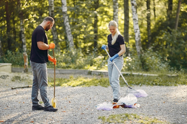 Foto gratuita la coppia raccoglie l'immondizia nei sacchetti di immondizia in parco