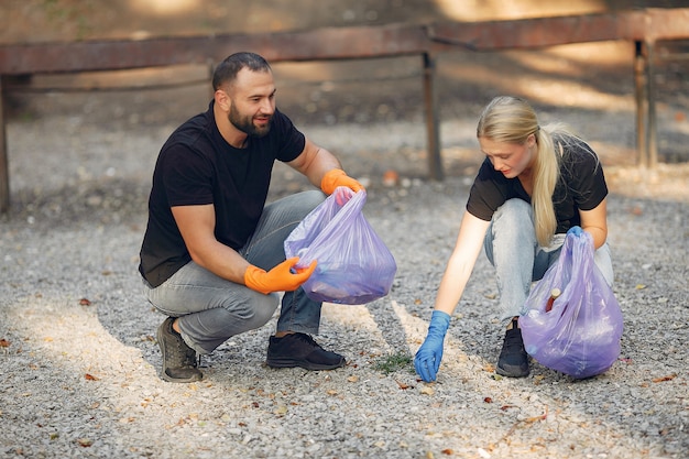 Бесплатное фото Пара собирает мусор в мешки для мусора в парке