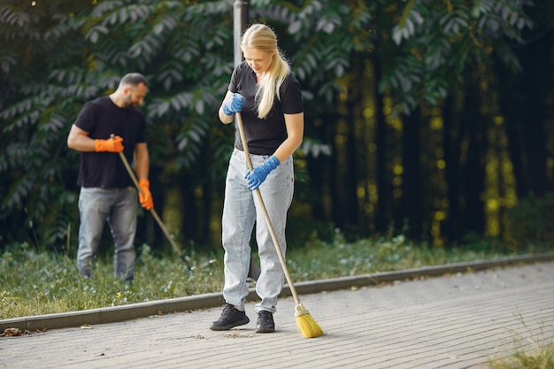 Free photo couple collects leaves and cleans the park