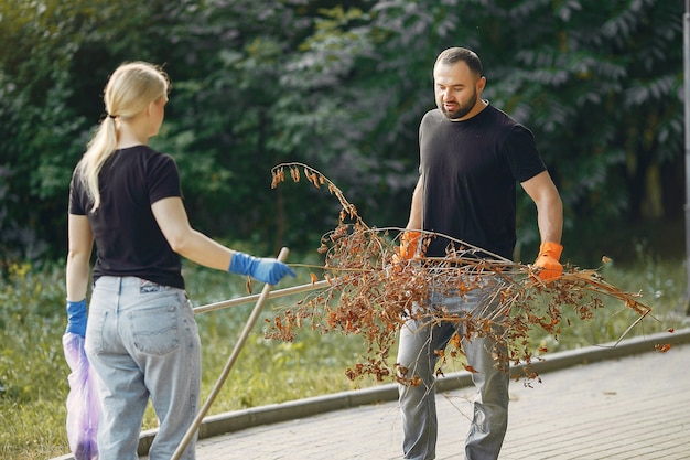 Free photo couple collects leaves and cleans the park