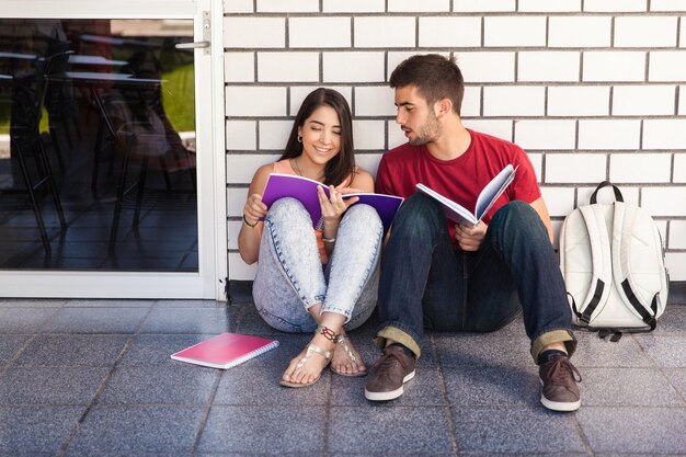 교실 밖에 앉아서 함께 공부하는 대학생 커플