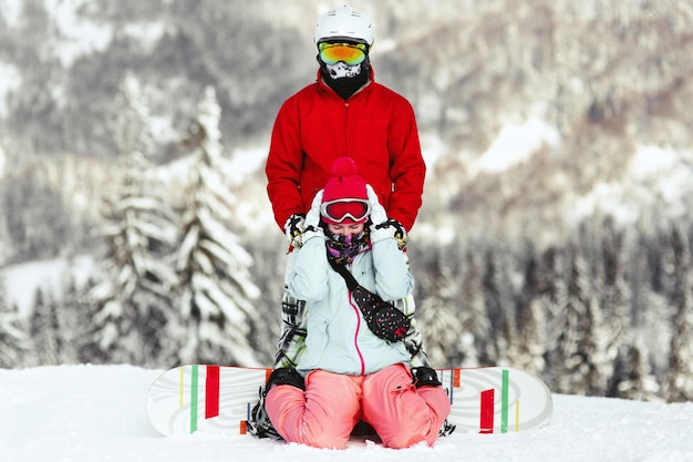 Couple in colorful ski suits poses on the hill somewhere in the mountains 