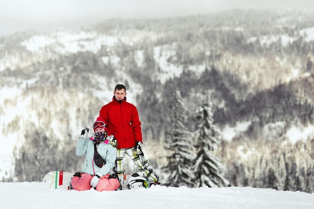 Couple in colorful ski suits poses on the hill somewhere in the mountains 