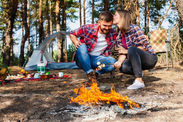 屋外の火でmarshmellowを調理するカップル