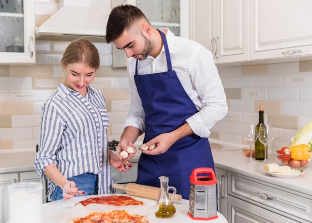 Couple cooking pizza in kitchen 