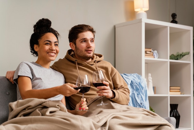 テレビを見たり、ワインを飲んだりするソファの上のカップル